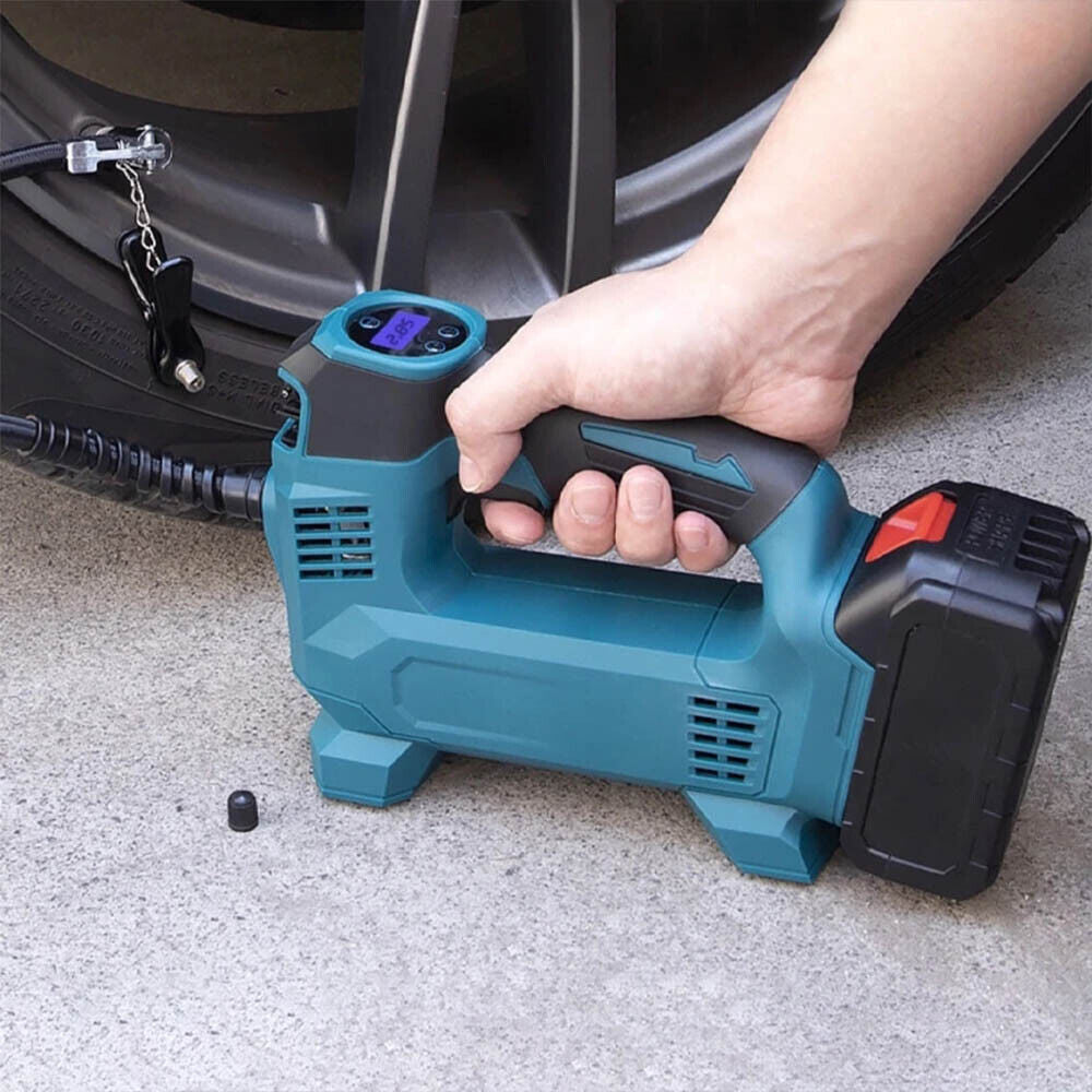 Hand holding a blue and black air pump near a car tire on a concrete surface.